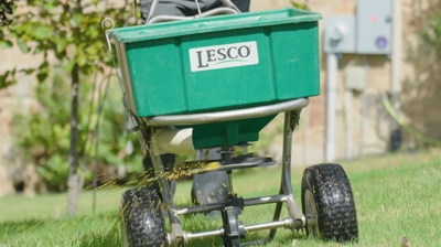 lawn care professional applying pre-emergent weed killer on grass