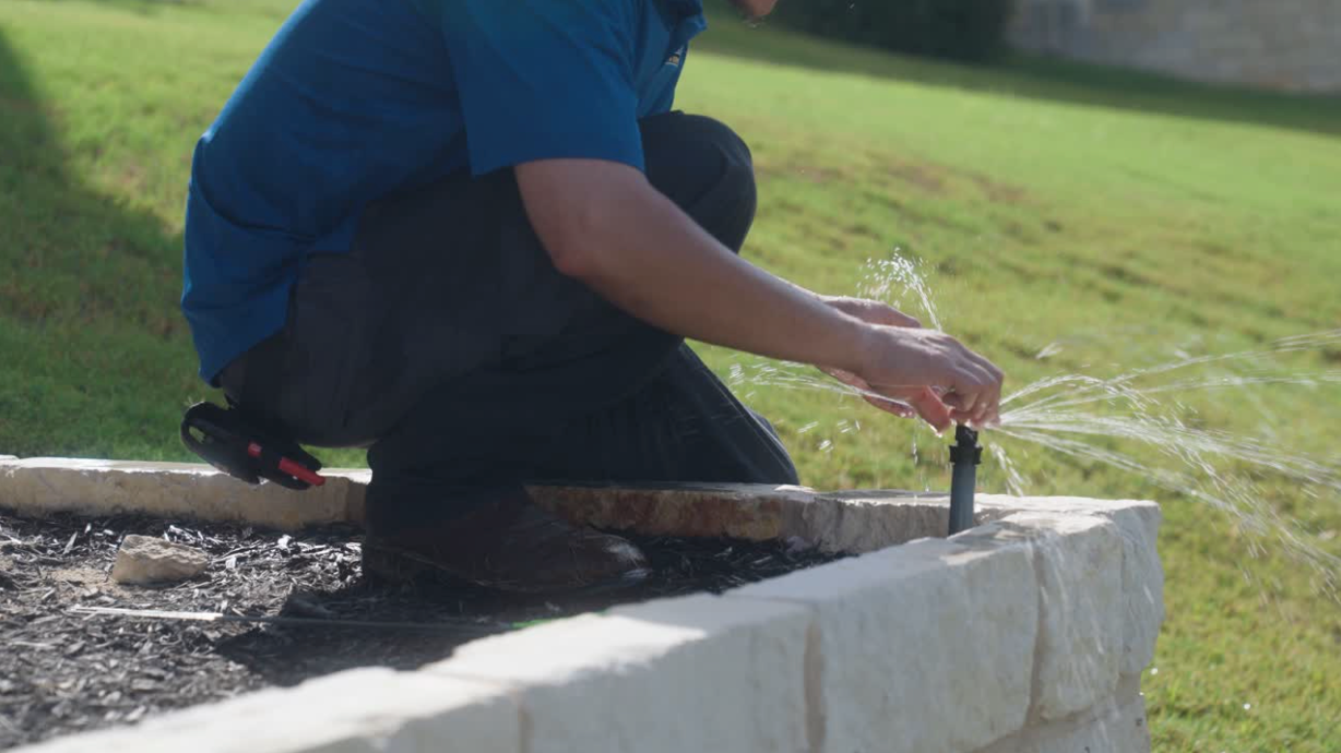 man in blue shirt repairing a sprinkler